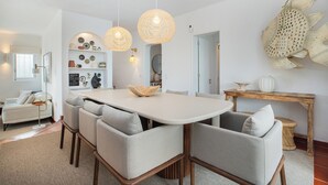 A modern dining area with a white table, grey upholstered chairs, and two wicker pendant lights. - Villa Óscar 4-bedroom with AC in lovely Lagos (Lagos)