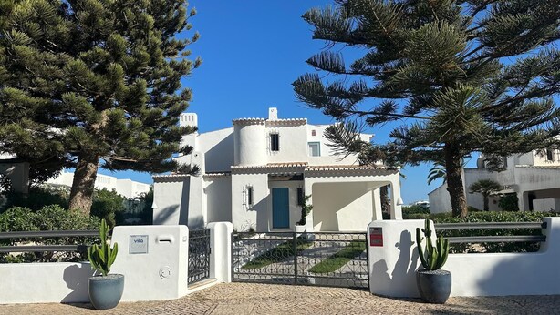 A white building with a blue door, surrounded by potted plants and trees. - Villa Óscar 4-bedroom with AC in lovely Lagos (Lagos)