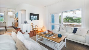 A modern living room with a white sofa, a wooden coffee table, and a TV mounted on the wall. - Villa Óscar 4-bedroom with AC in lovely Lagos (Lagos)