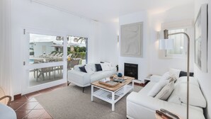 A modern living room with white furniture, a fireplace, and a view of a pool and outdoor seating. - Villa Óscar 4-bedroom with AC in lovely Lagos (Lagos)