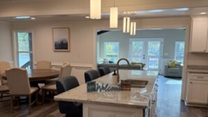 Una cucina moderna con isola centrale, illuminazione a sospensione e vista sull'area pranzo.