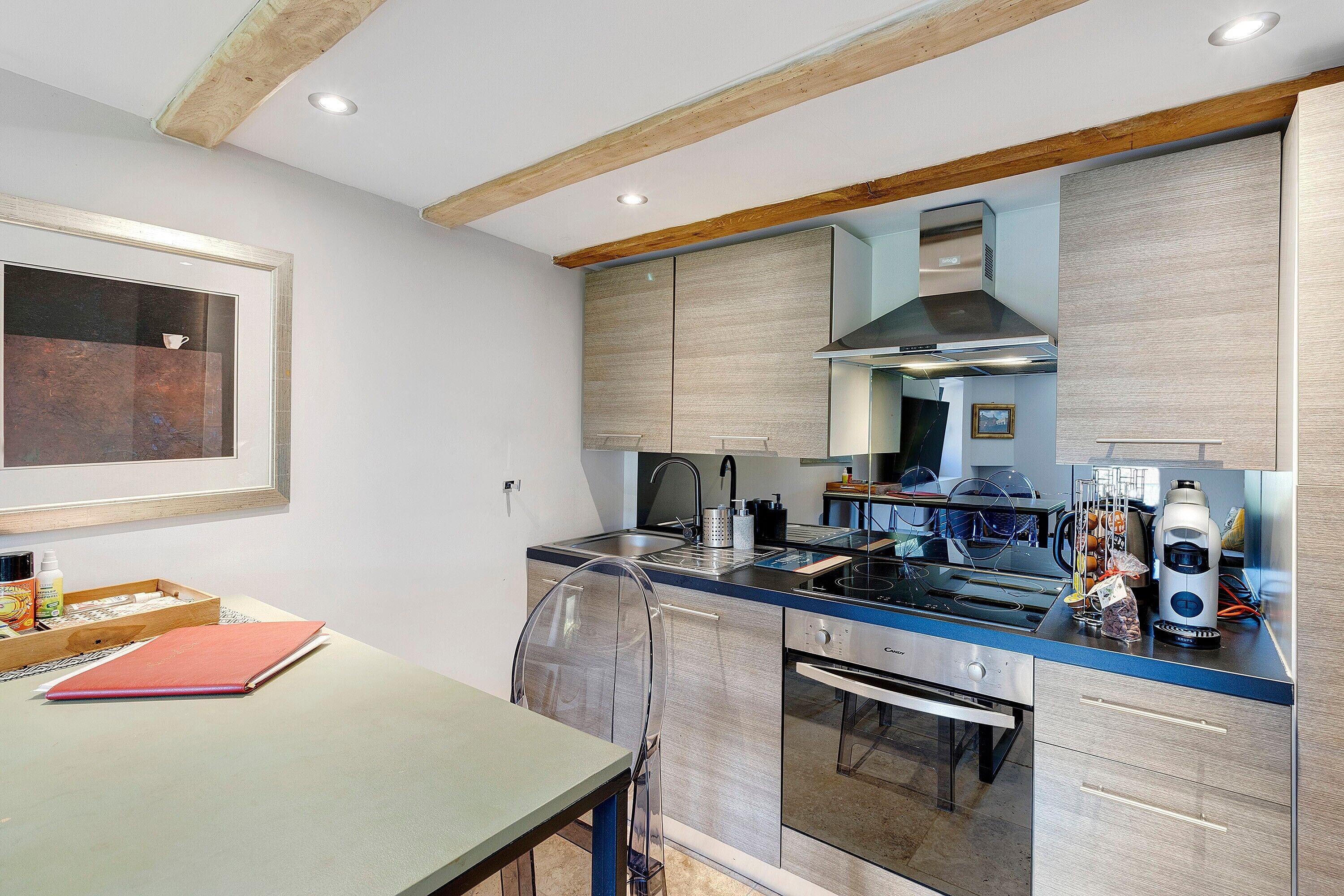 A modern kitchen with stainless steel appliances, wooden beams, and a dining area with a table and chairs.