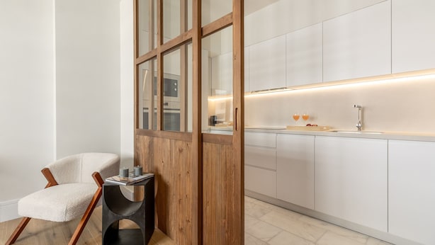 Een moderne keuken met witte kastjes, een raam met houten kader en een ingebouwd spoelbak.