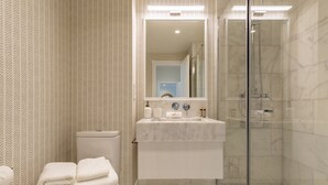 Een moderne badkamer met een douchecabine van glas, een witte wastafel en een toilet.