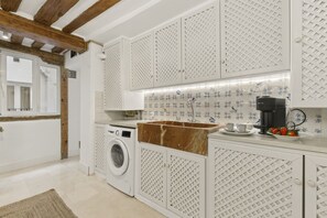 Una cocina compacta con lavadora, cafetera y lavamanos.