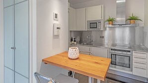 Una cucina moderna con un tavolo di legno, elettrodomestici in acciaio inossidabile e un forno a microonde.