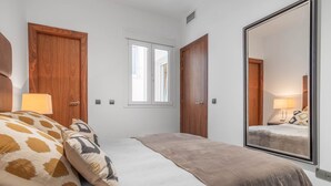 Una camera da letto con un letto, due porte in legno, una finestra e un grande specchio.