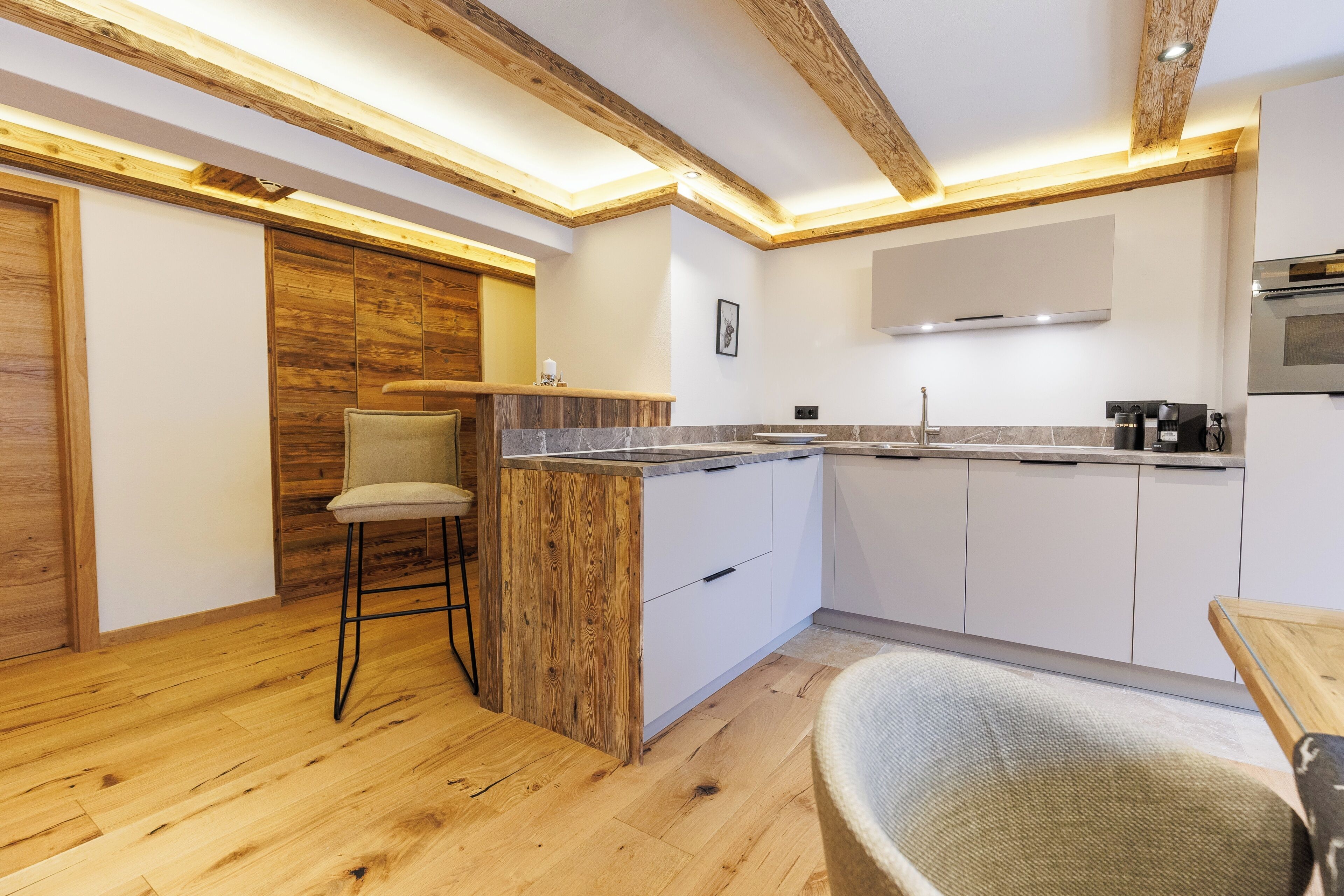 A modern kitchen with wooden beams, white cabinets, and a bar area.