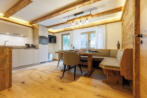 Una cucina moderna con travi in legno, un'area pranzo con tavolo e sedie in legno e un forno integrato.