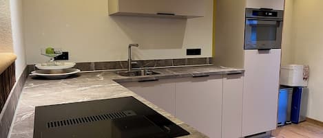 Una cuina moderna amb forn integrat, un rentapeus i una placa d'inducció negra.