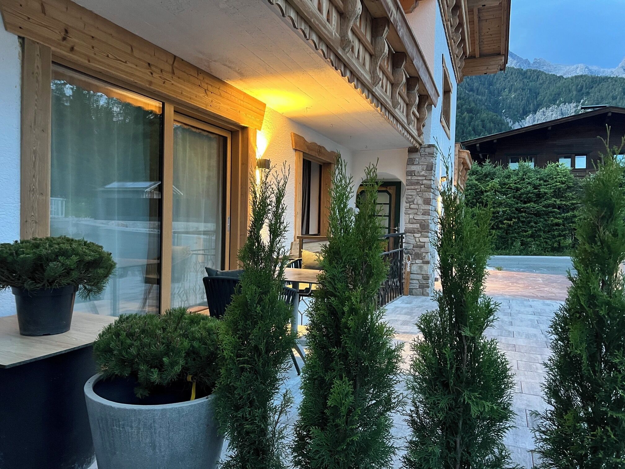 Un edificio con fachada de madera, ventanas grandes y plantas en macetas.