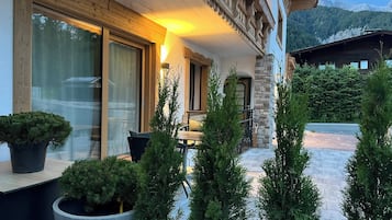 Un edificio con fachada de madera, ventanas grandes y plantas en macetas.