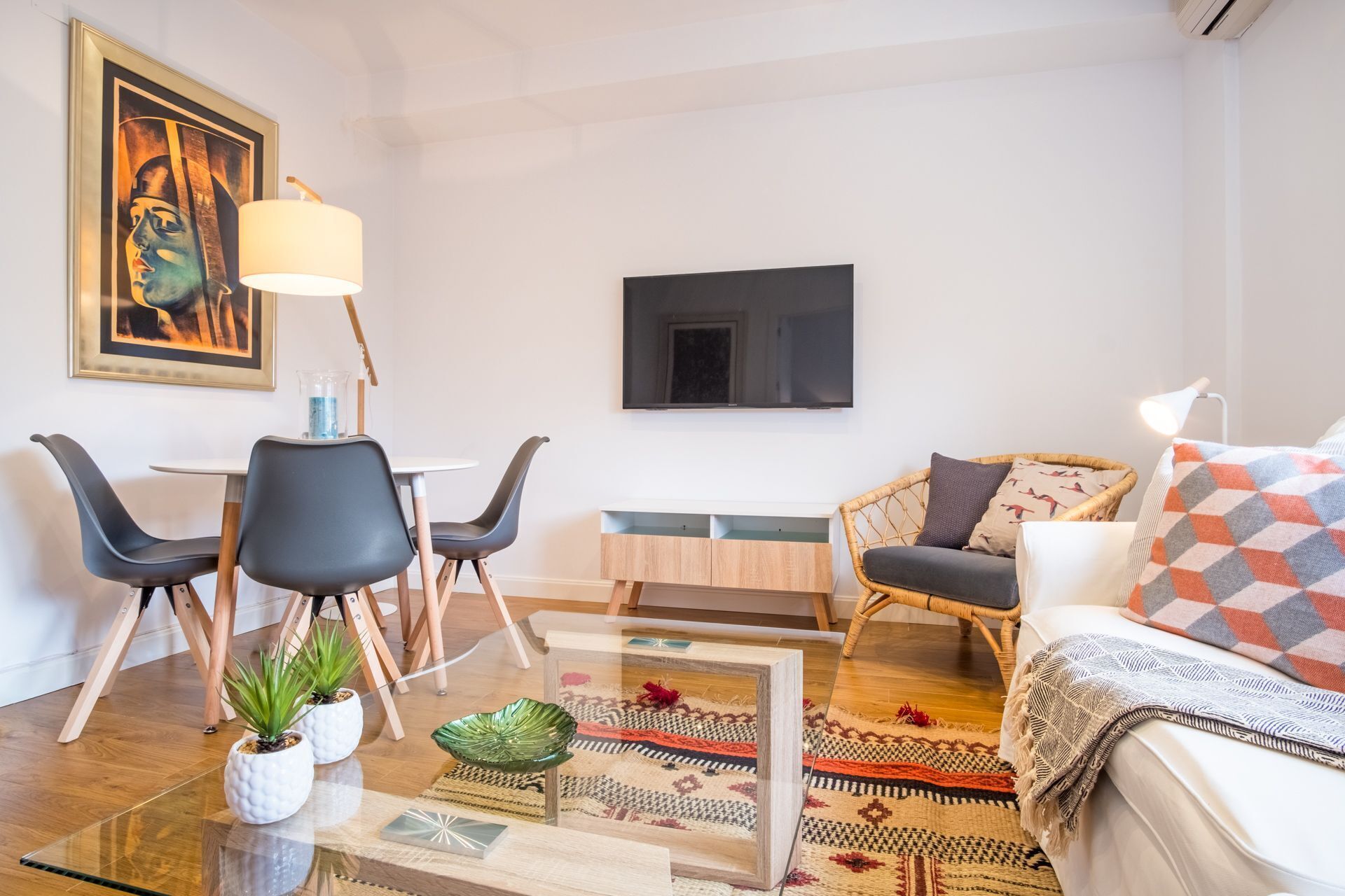 Een moderne woonkamer met een eethoek, een wandgemonteerde flatscreen-tv en een comfortabele zithoek.