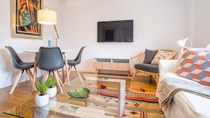 Een moderne woonkamer met een eethoek, een wandgemonteerde flatscreen-tv en een comfortabele zithoek.