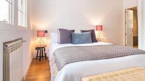 Een slaapkamer met een bed, twee bedlampen, een radiator en een raam.