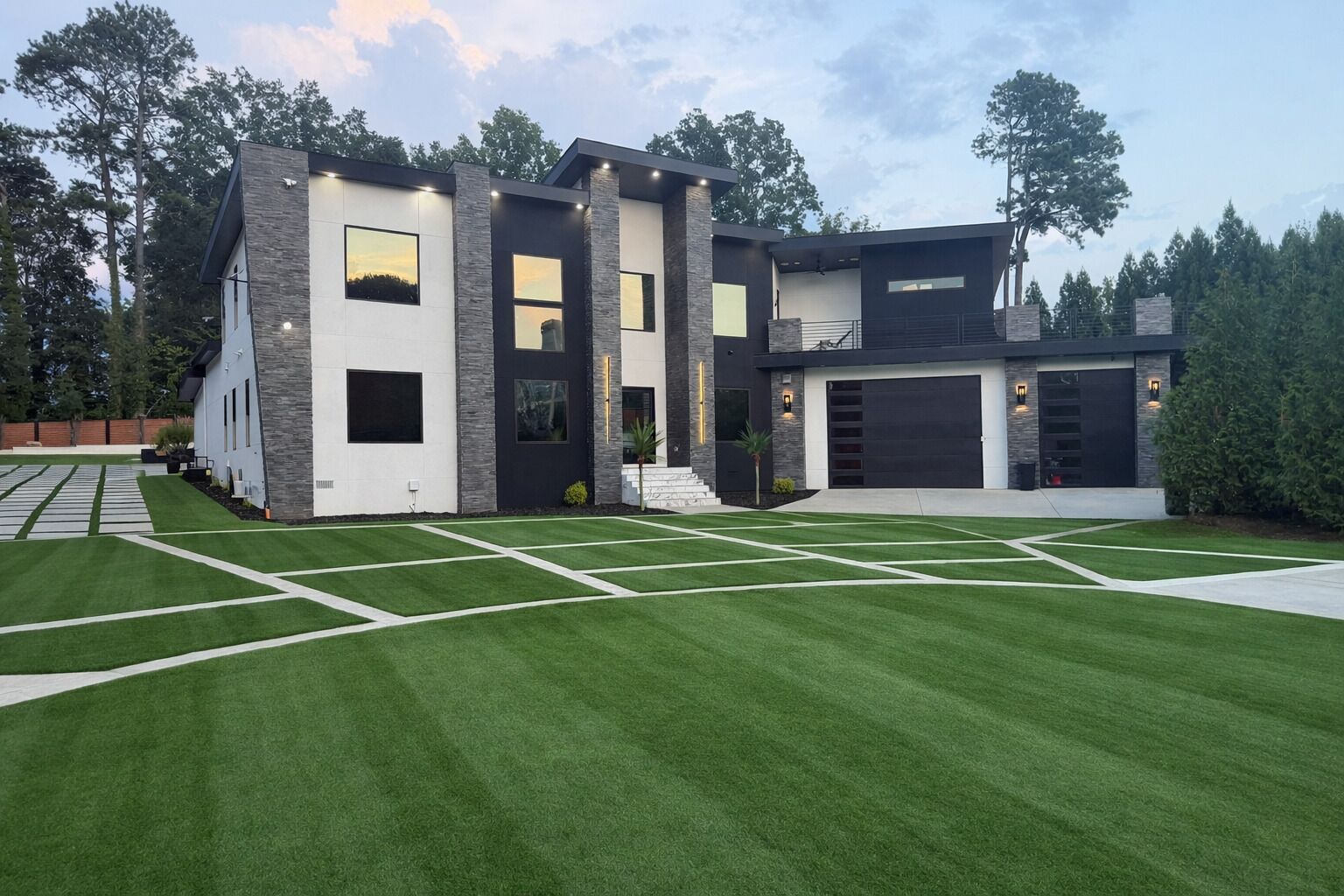 Uma casa moderna de dois andares com garagem, gramado bem cuidado e entrada para carros.
