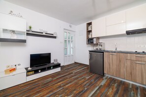 Eine moderne Küche mit weißen Schränken, einer eingebauten Mikrowelle und einem Kühlschrank.