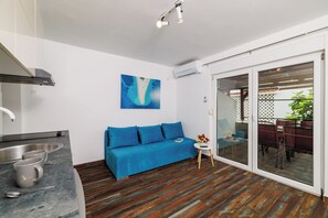 Eine moderne Küche mit Einbauherd, einem blauen Sofa und einem Essbereich mit Glastür zum Außenbereich.