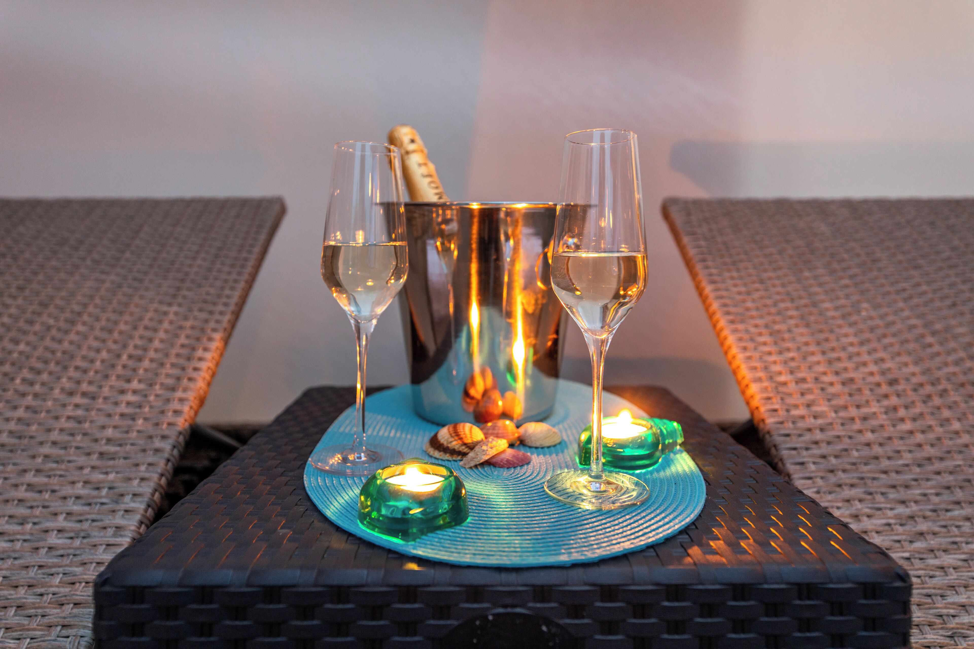 Ett bord med två glas vitt vin, en flaska champagne och dekorativa ljus.