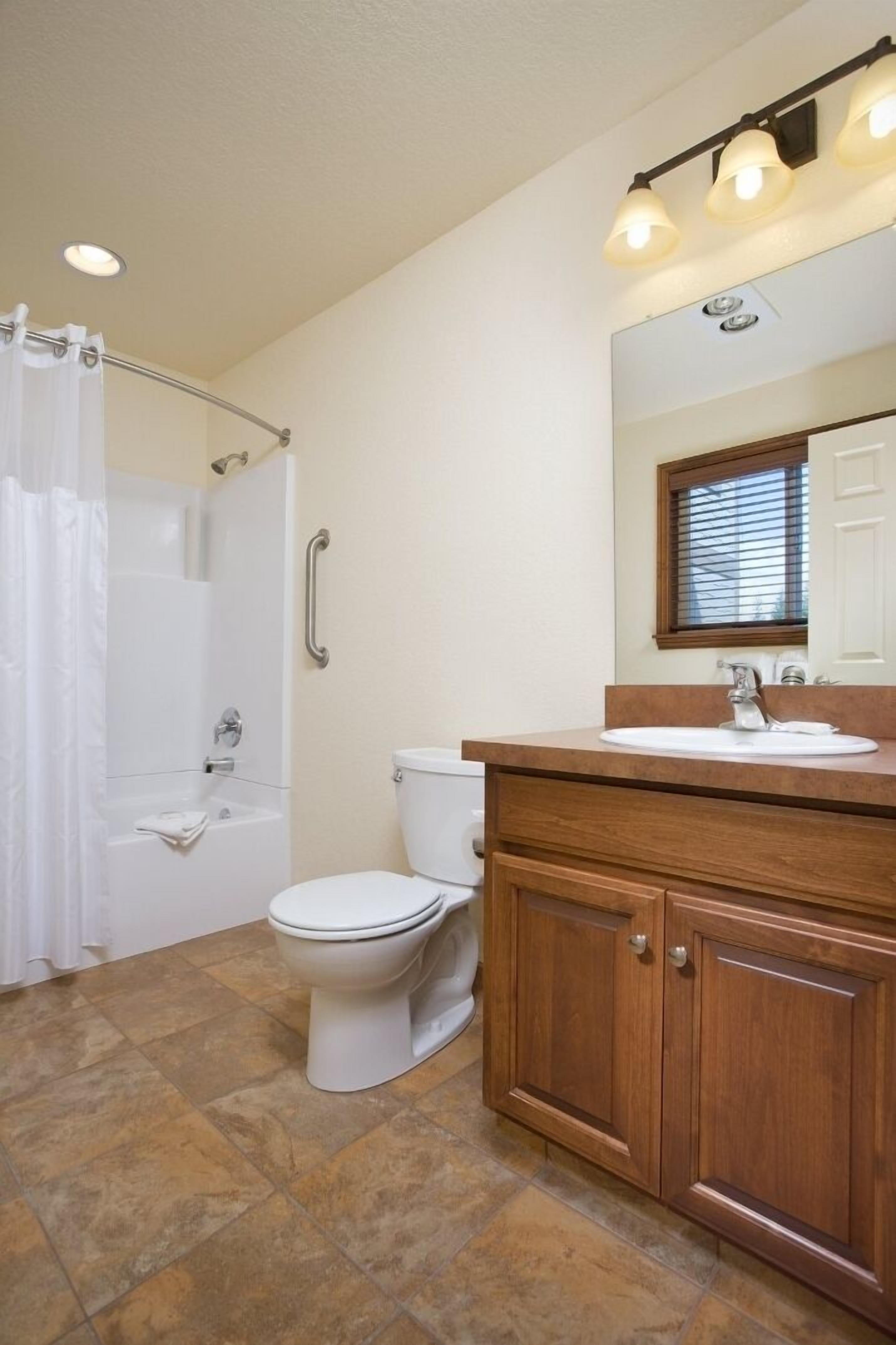 Une salle de bain équipée d’une douche, de toilettes et d’un meuble-lavabo avec un miroir.