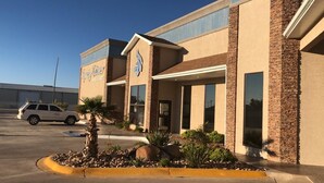 Un hotel con fachada moderna, estacionamiento y cielo despejado.