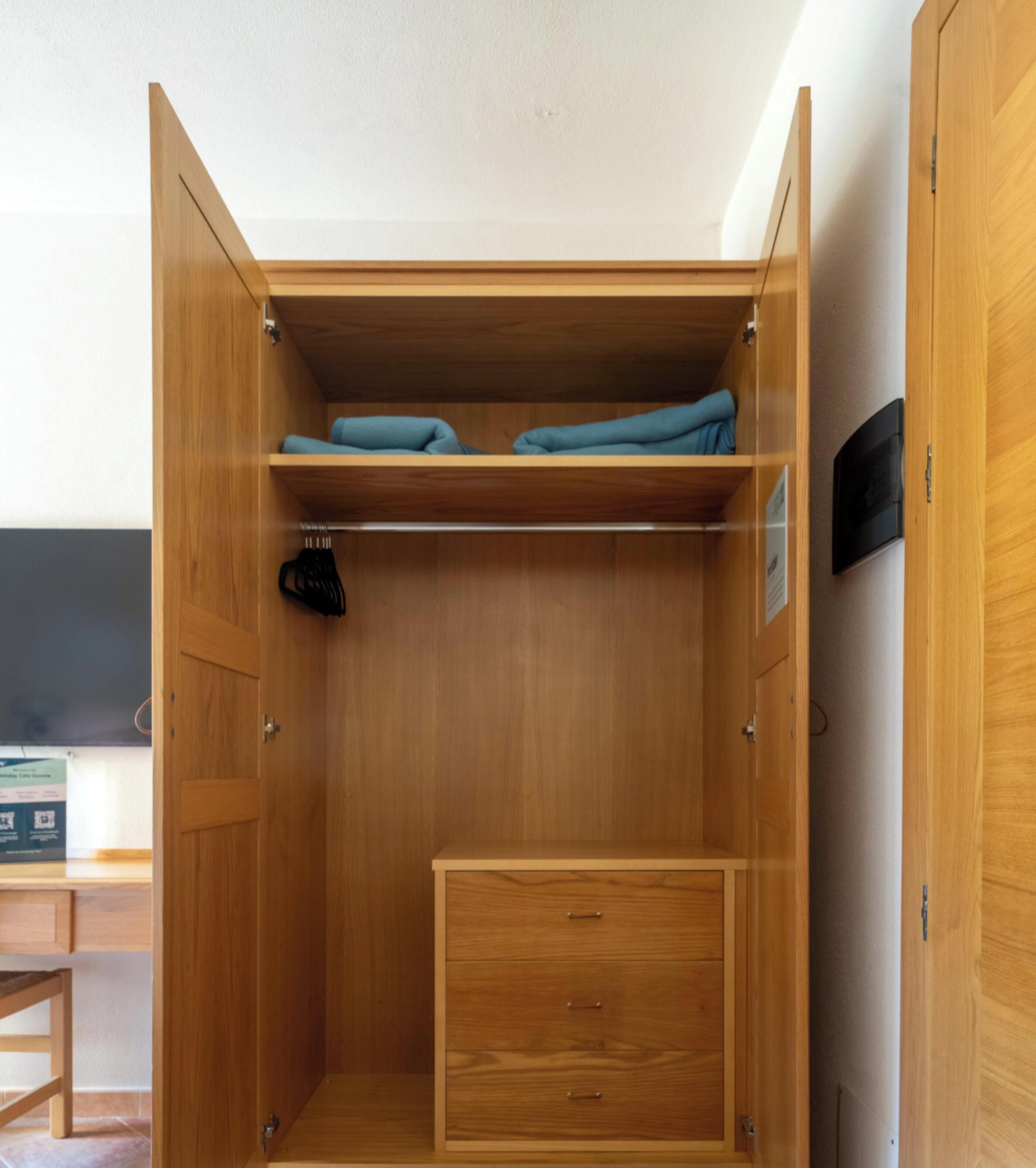 Een houten garderobe met planken, een kledingroede en een lade.