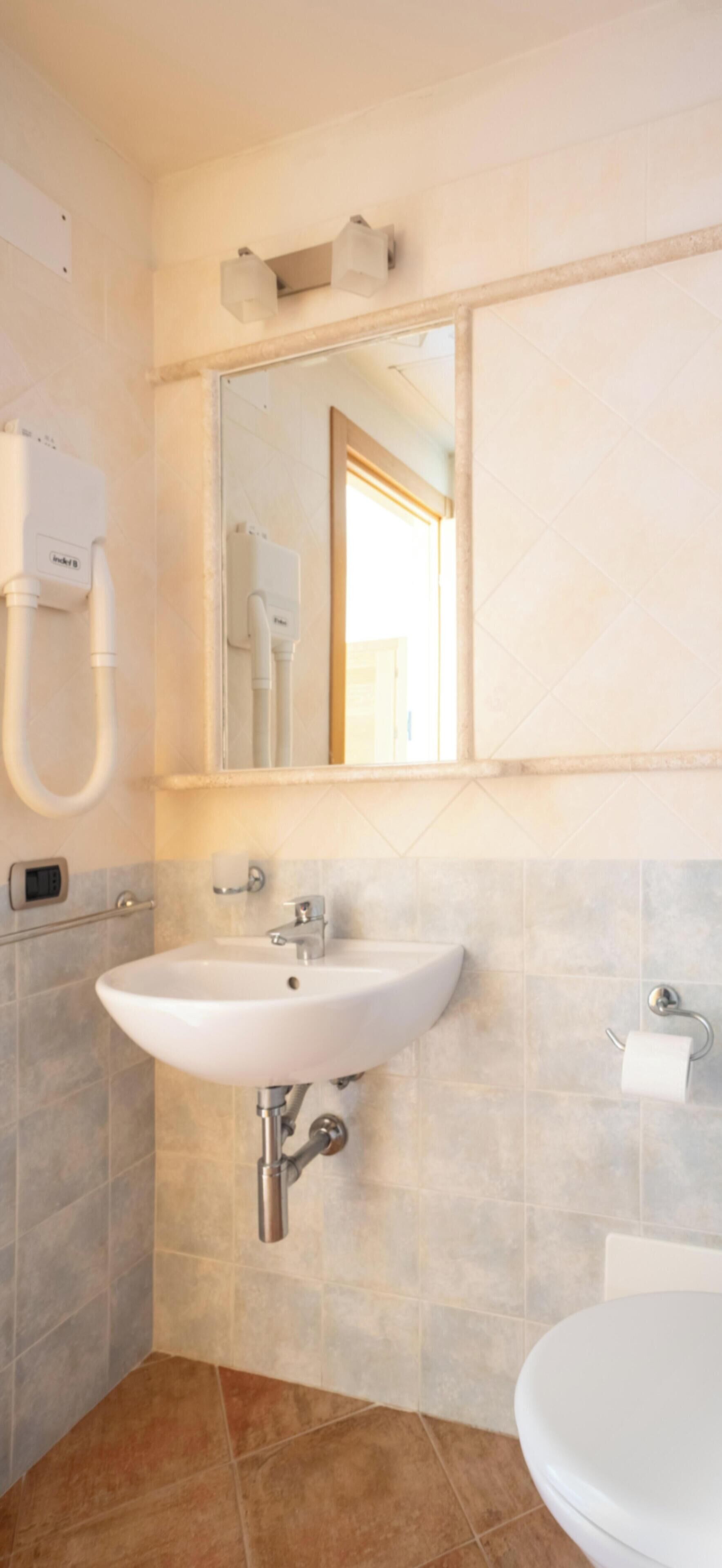 Une salle de bain avec un lavabo blanc, un miroir et des toilettes.