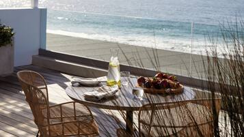 A terrace with a table and chairs, overlooking the ocean.