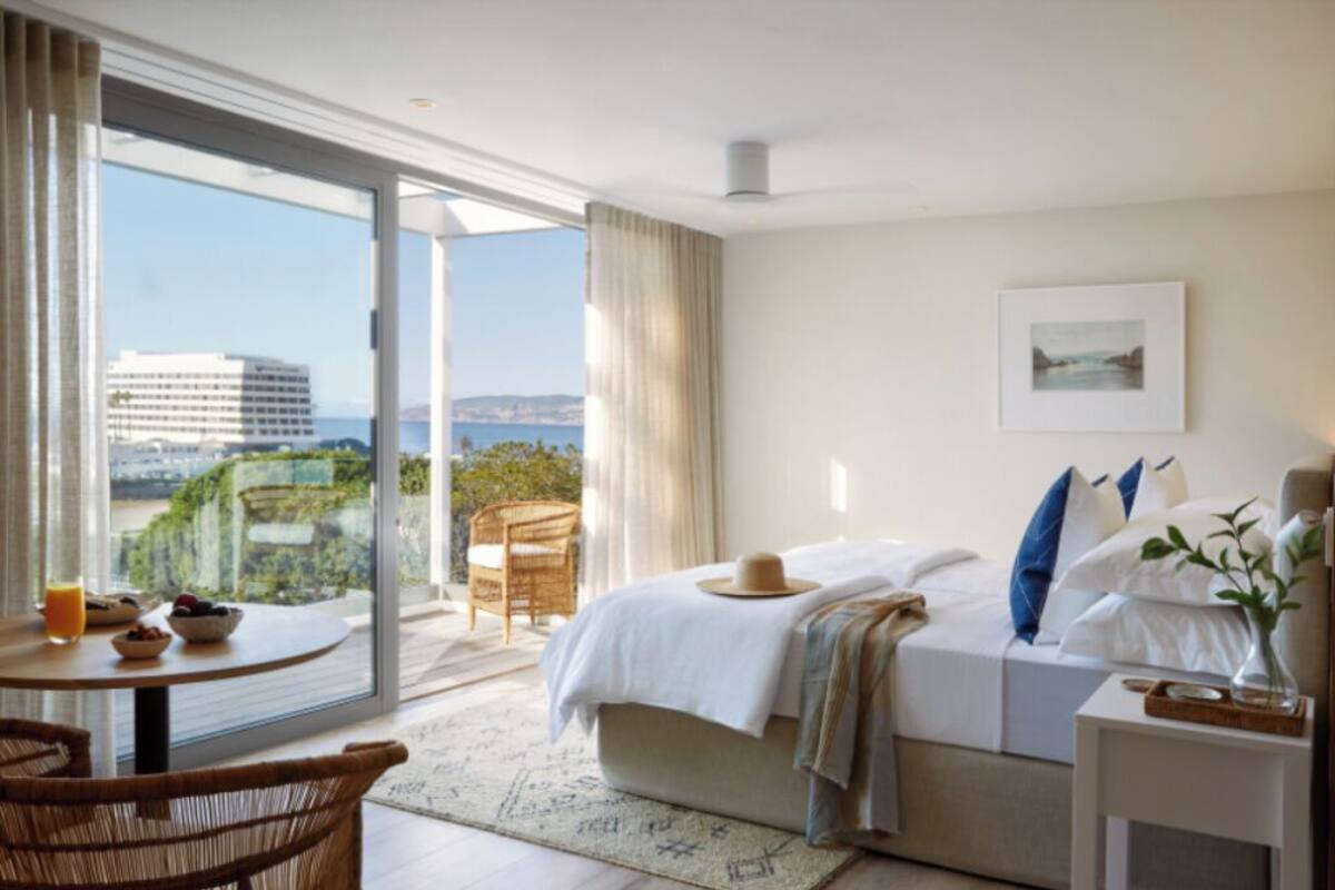 Una camera d'hotel con un letto, un tavolo da pranzo, una sedia e vista sulla città.