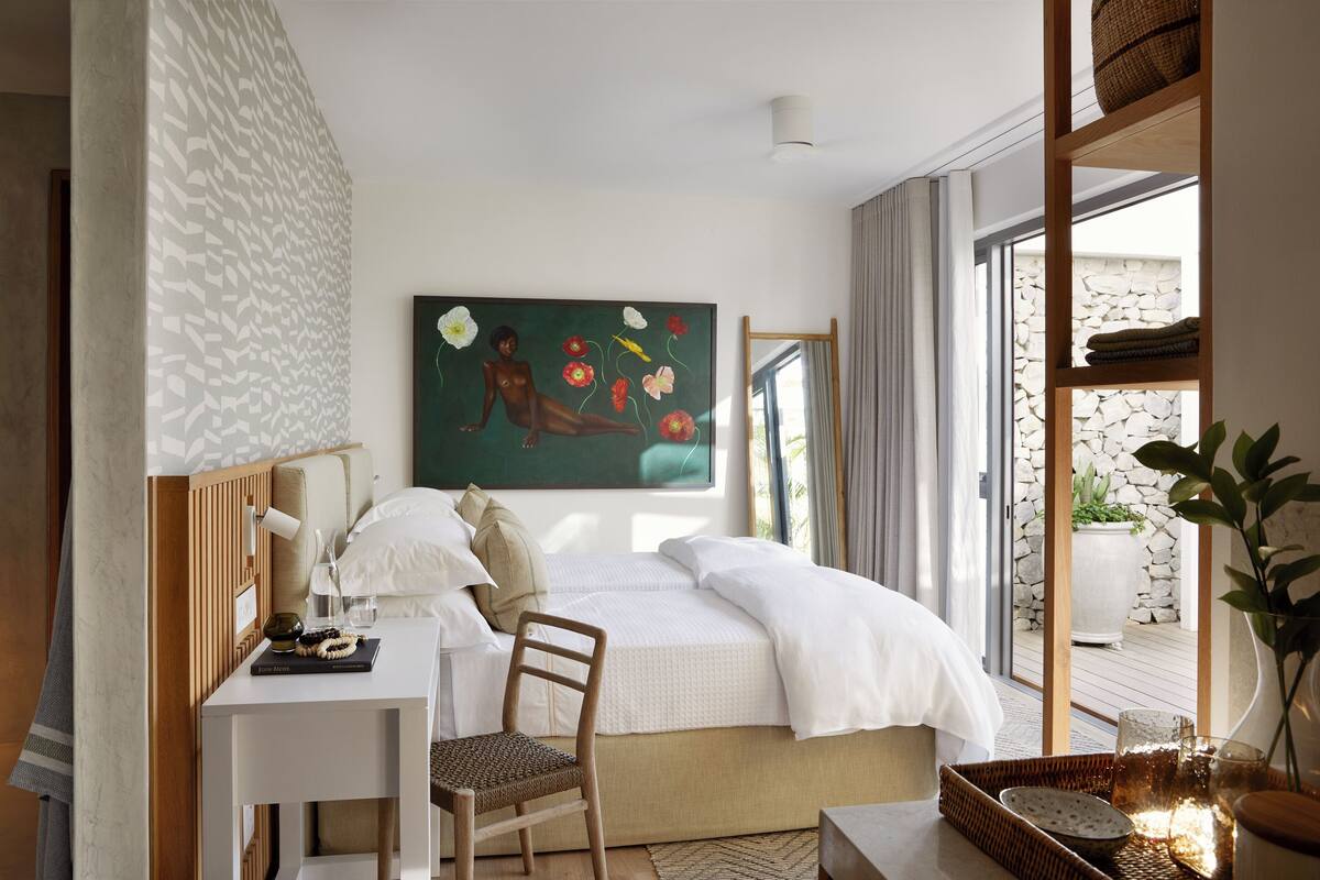 Una camera da letto con un letto, una scrivania, una sedia, un quadro e vista sull'esterno.