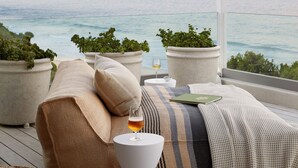 A balcony with a view of the sea, potted plants, a glass of wine, and a cozy seating area. - Walkers Beach (Plettenberg Bay)