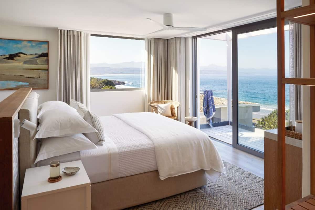 Una camera da letto con un letto grande, vista mare e un balcone con una sedia.