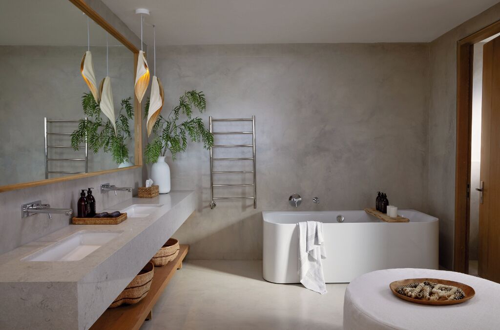 A modern bathroom with a large bathtub, two sinks, a mirror, and a plant.