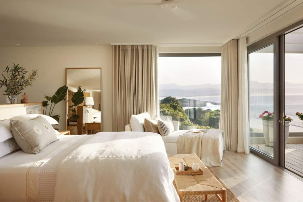 Una camera d'albergo con un letto grande, un'area salotto, un balcone con vista e un ampio specchio.