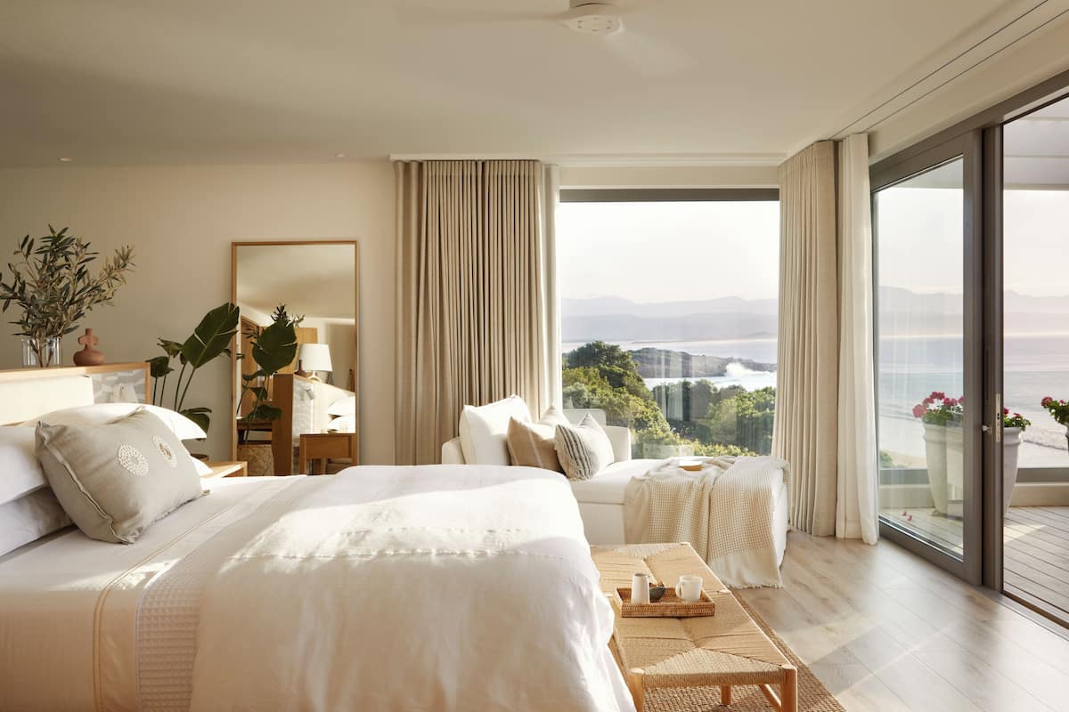 Ampia camera da letto con un grande letto, un comodino, una sedia, vista sull'esterno e un balcone.