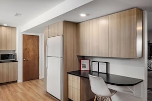 A modern kitchen with wooden cabinets, a white refrigerator, a microwave, and a black countertop. - Located next to Knox Mountain. Two bedrooms one bathroom peaceful great location (Kelowna)