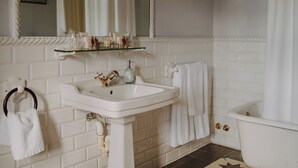A bathroom with a white sink, a mirror, a bathtub, and a towel rack. - Hotel Boutique Palacio de Caranceja (Reocín)