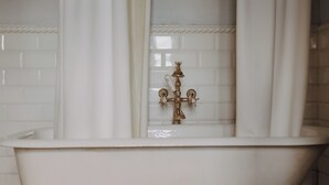 Una bañera blanca con grifo de latón y cortina de ducha.