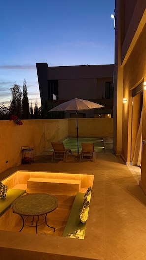 Un espace extérieur aménagé avec une terrasse, une piscine, des chaises longues et une table.