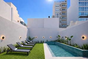 A rooftop pool area with lounge chairs and a small pool, surrounded by walls and greenery. - Trendy Apartments in Palermo Hollywood by BueRentals (Buenos Aires)