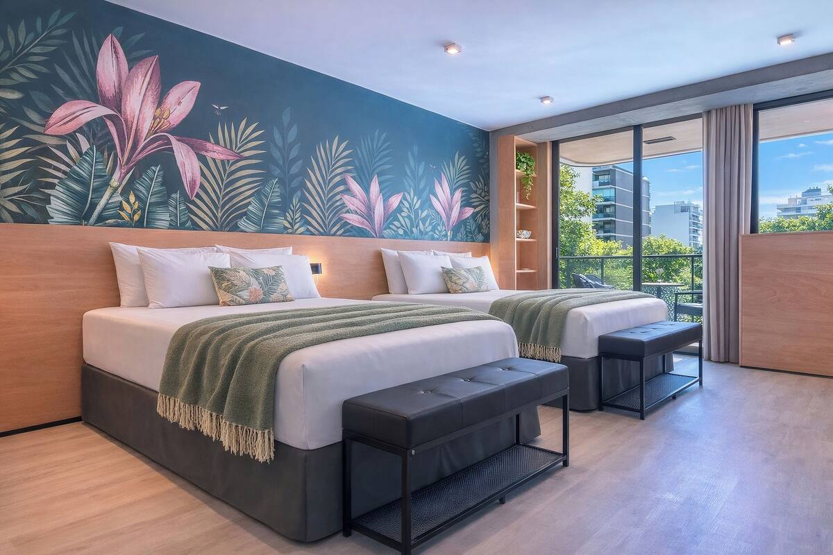 Une chambre moderne avec deux lits, un banc, une fresque murale et un balcon avec vue.