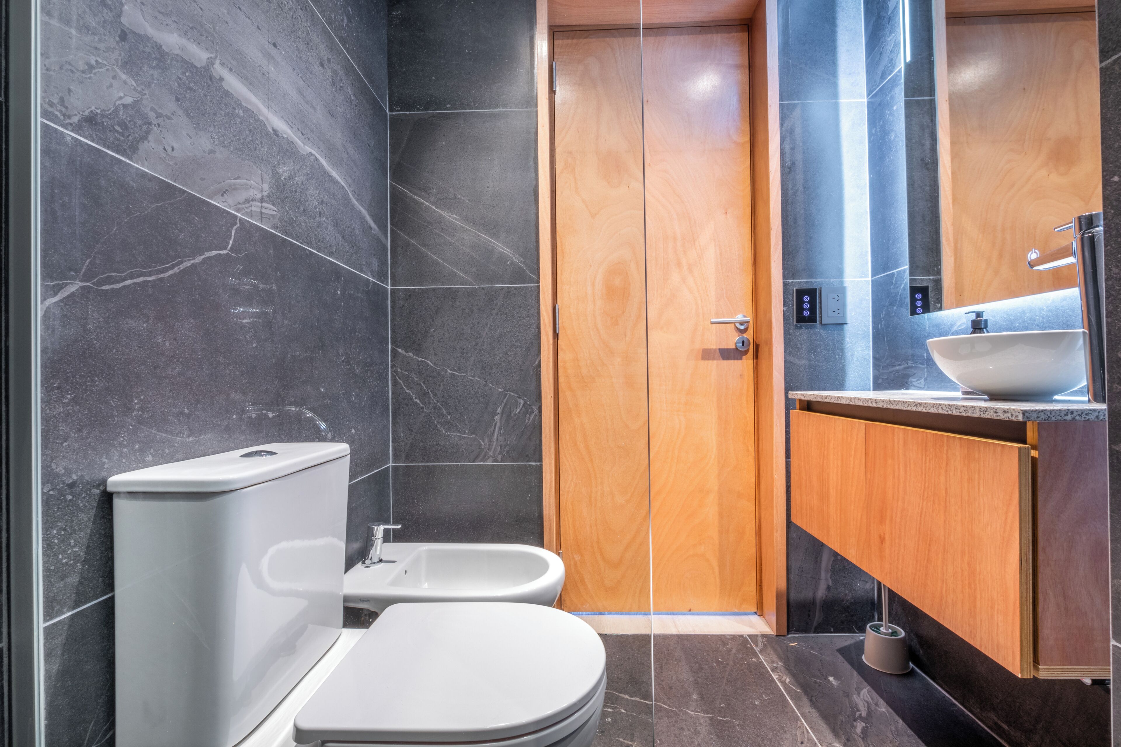 Een moderne badkamer met toilet, hygiëneschuimer en wastafel.