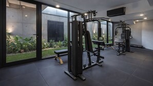 Ein modernes Fitnessstudio mit Trainingsgeräten, großen Fenstern und Blick auf einen Garten.