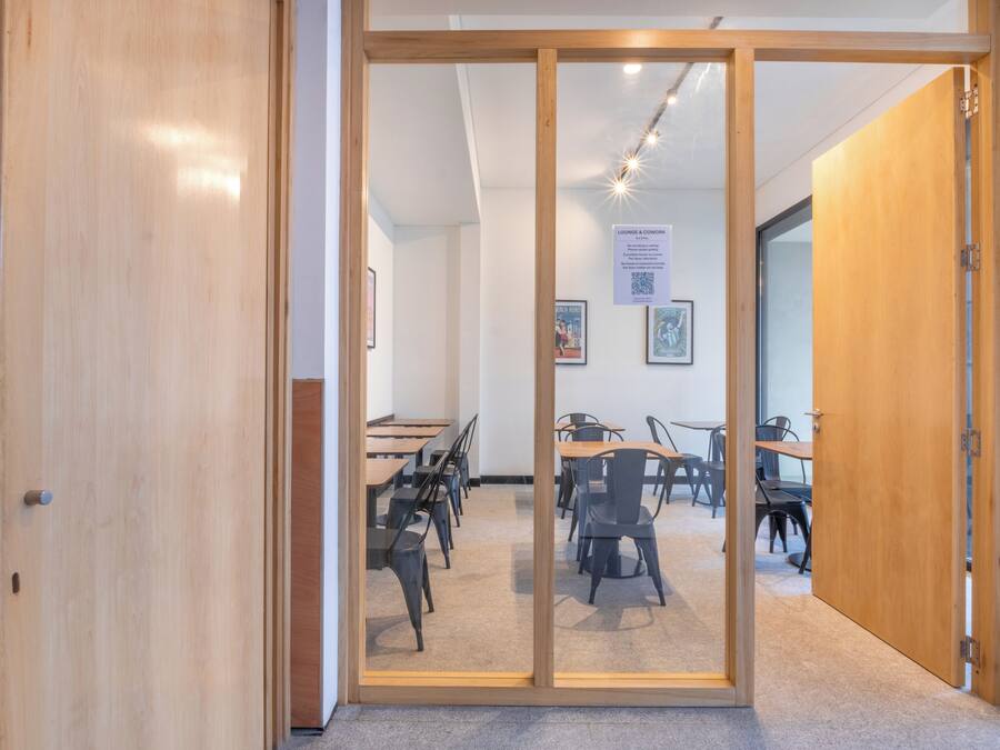 Una habitación con puerta de cristal que da a un comedor con mesas y sillas.