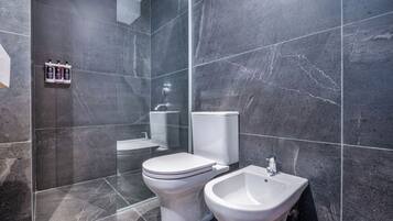 A modern bathroom with a toilet, bidet, and shower.