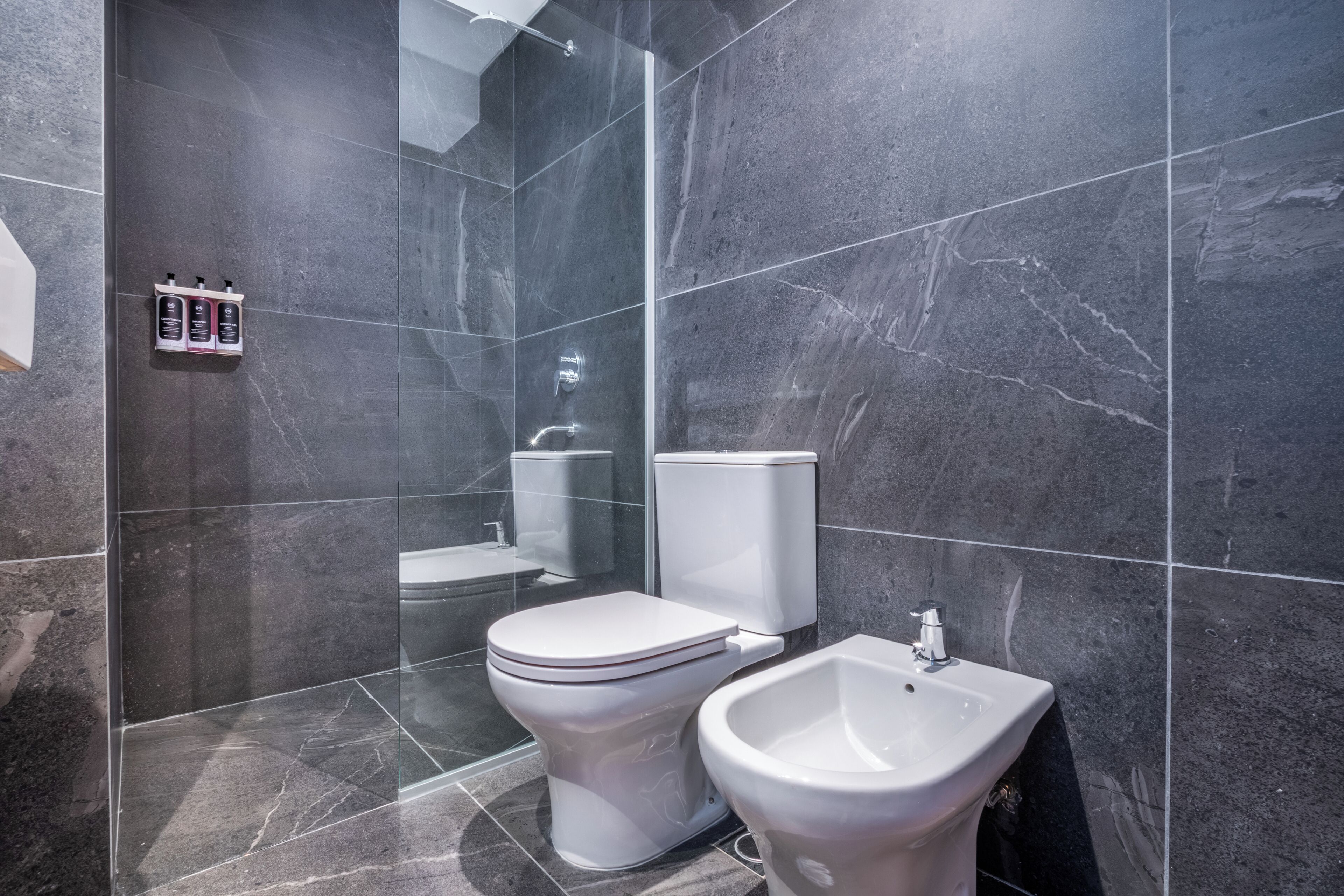A modern bathroom with a toilet, bidet, and shower.