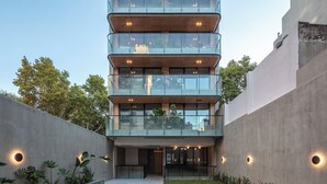 Un edificio de varios pisos con balcones, piscina y jardín.