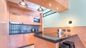 Una cocina moderna con armarios de madera, encimera negra y dos taburetes de bar.