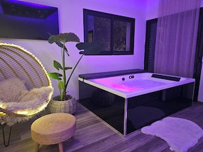 A modern room with a massage table, a hanging chair, and a potted plant.
