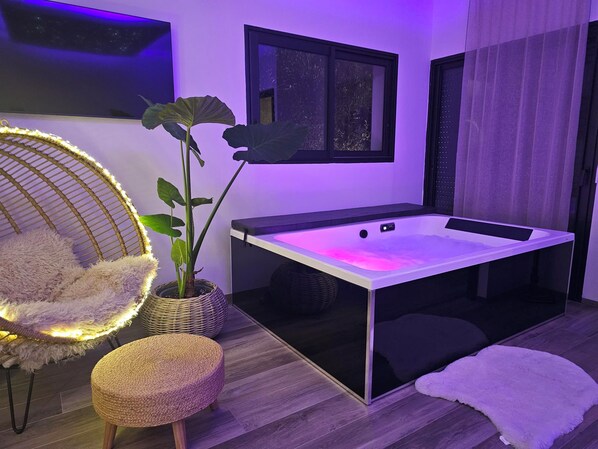 Habitació moderna amb una massatge, una cadira penjant i una planta en test.